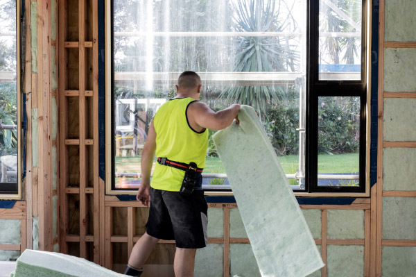 New Build Insulation, worker holding Greenstuf insulation inside a new build, by Healthy Homes Tai Tokerau